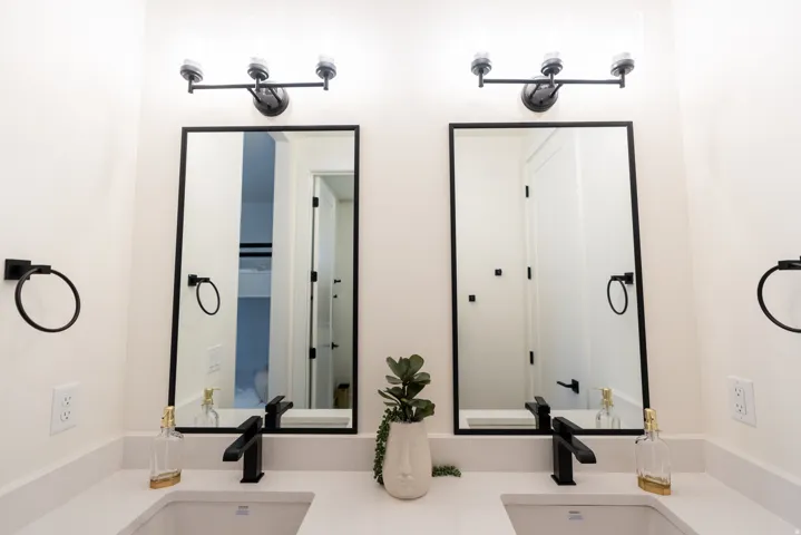 Dual vanity with rectangular undermount sinks, stone countertops, matte black faucets, and rectangular framed mirrors