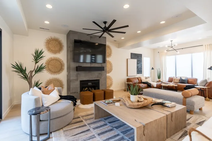 Spacious living area featuring a stone-clad fireplace, recessed lighting, and a prominent ceiling fan