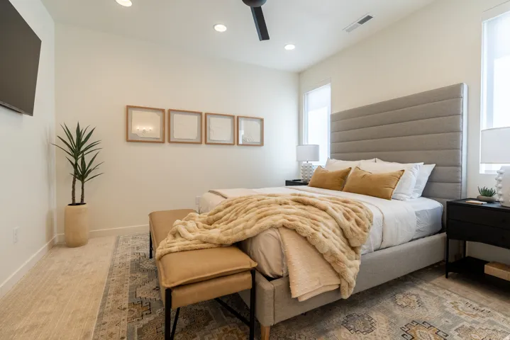 Recessed lighting, ceiling fan, wood-finish flooring, two window openings, and an upholstered headboard