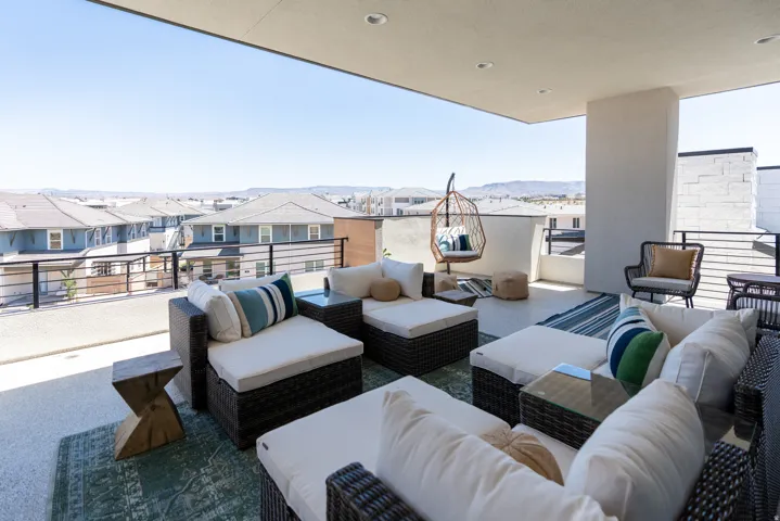 Spacious outdoor patio featuring an expansive overhang, modern railing, and mountain backdrop