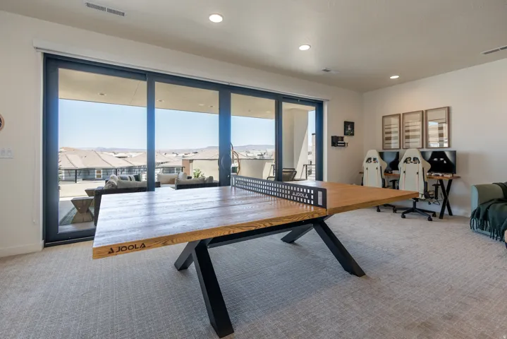 Expansive glass sliding doors, recessed lighting, neutral carpet, and a light-colored wall finish