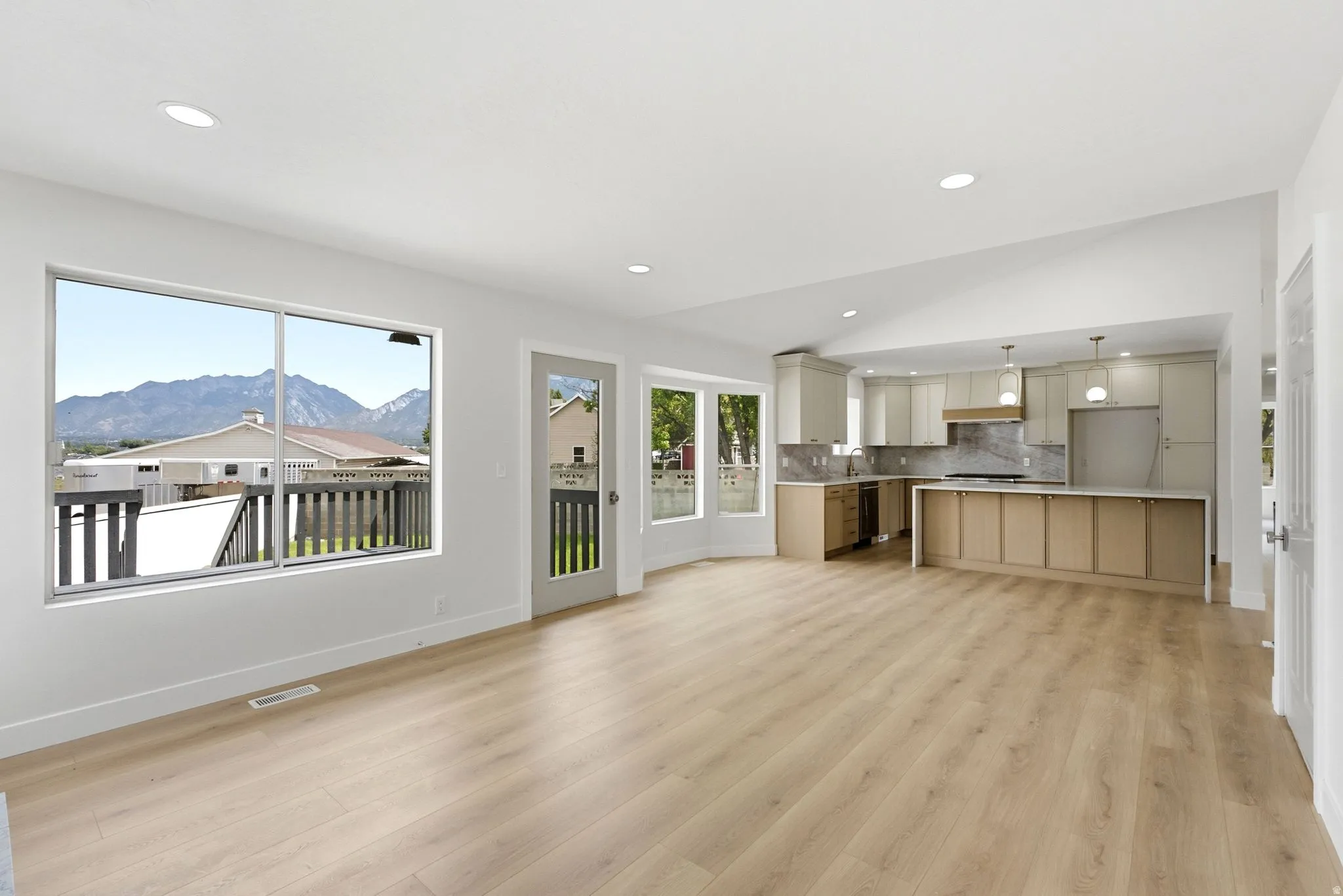 Open-concept living area with wood-finish flooring, vaulted ceiling, and recessed lighting