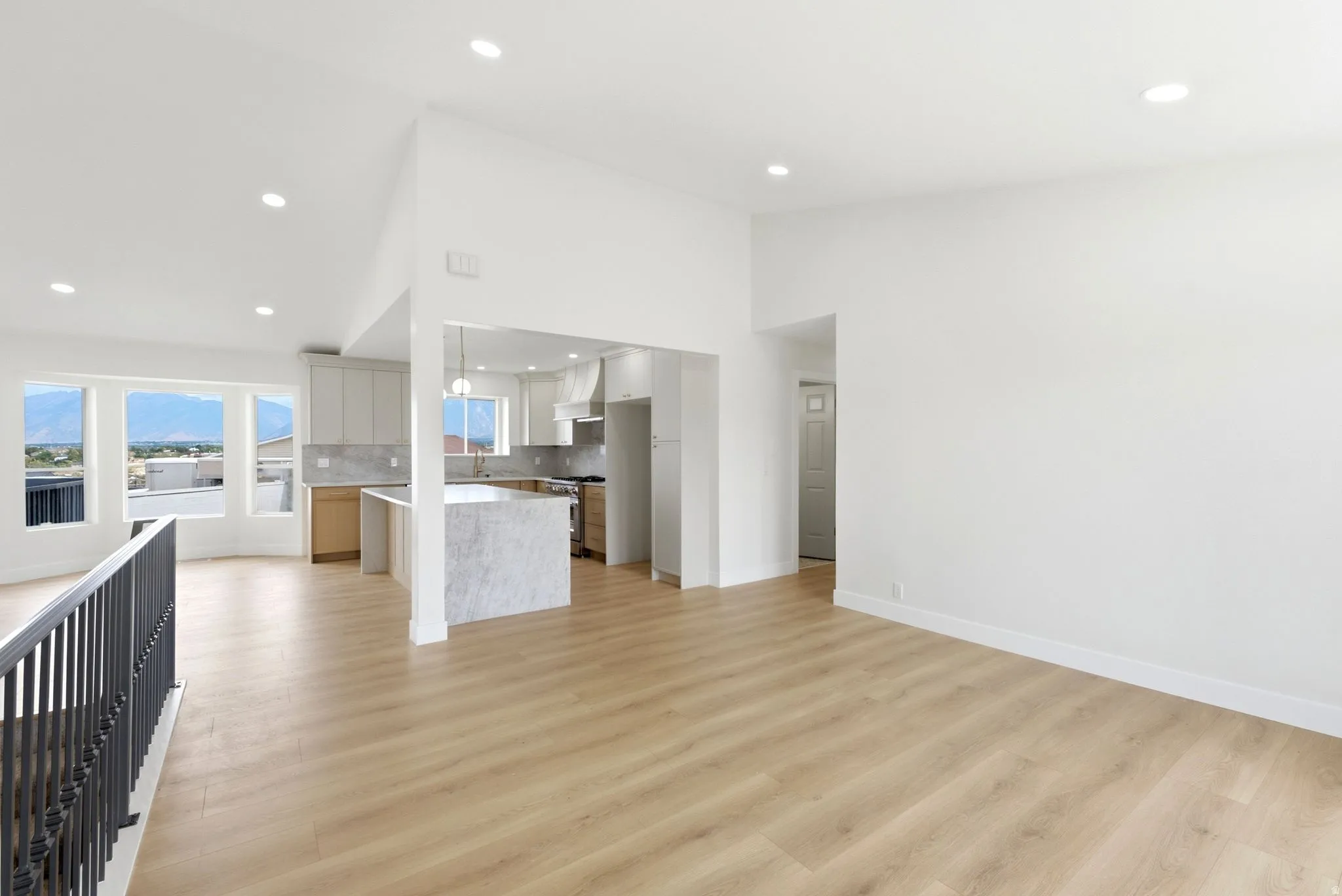 Open-concept living area with wood-finish flooring, recessed lighting, and a kitchen featuring a large island with stone finish