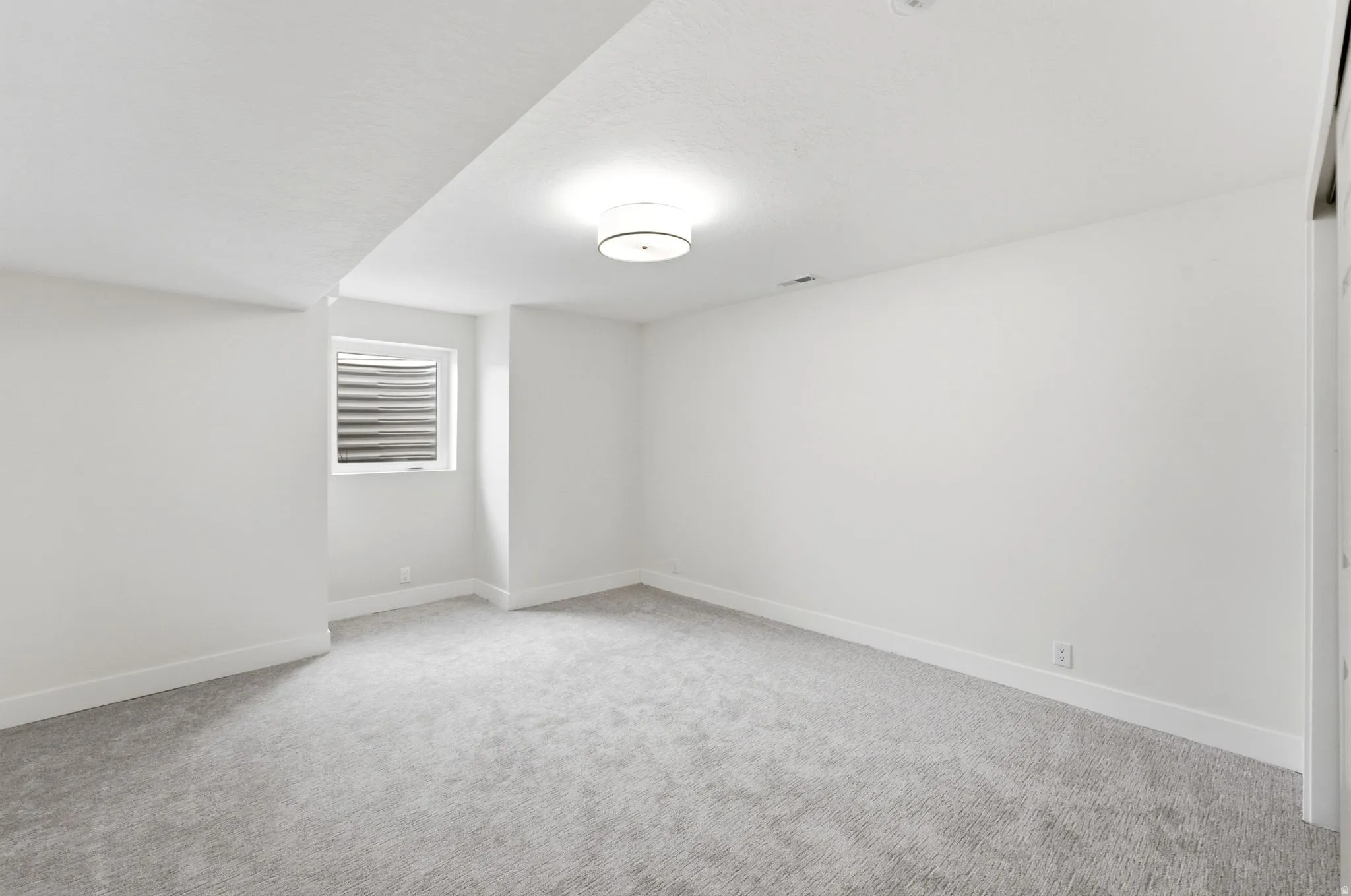 Recessed window with white trim, light gray carpet flooring, and a semi-flush mount ceiling fixture