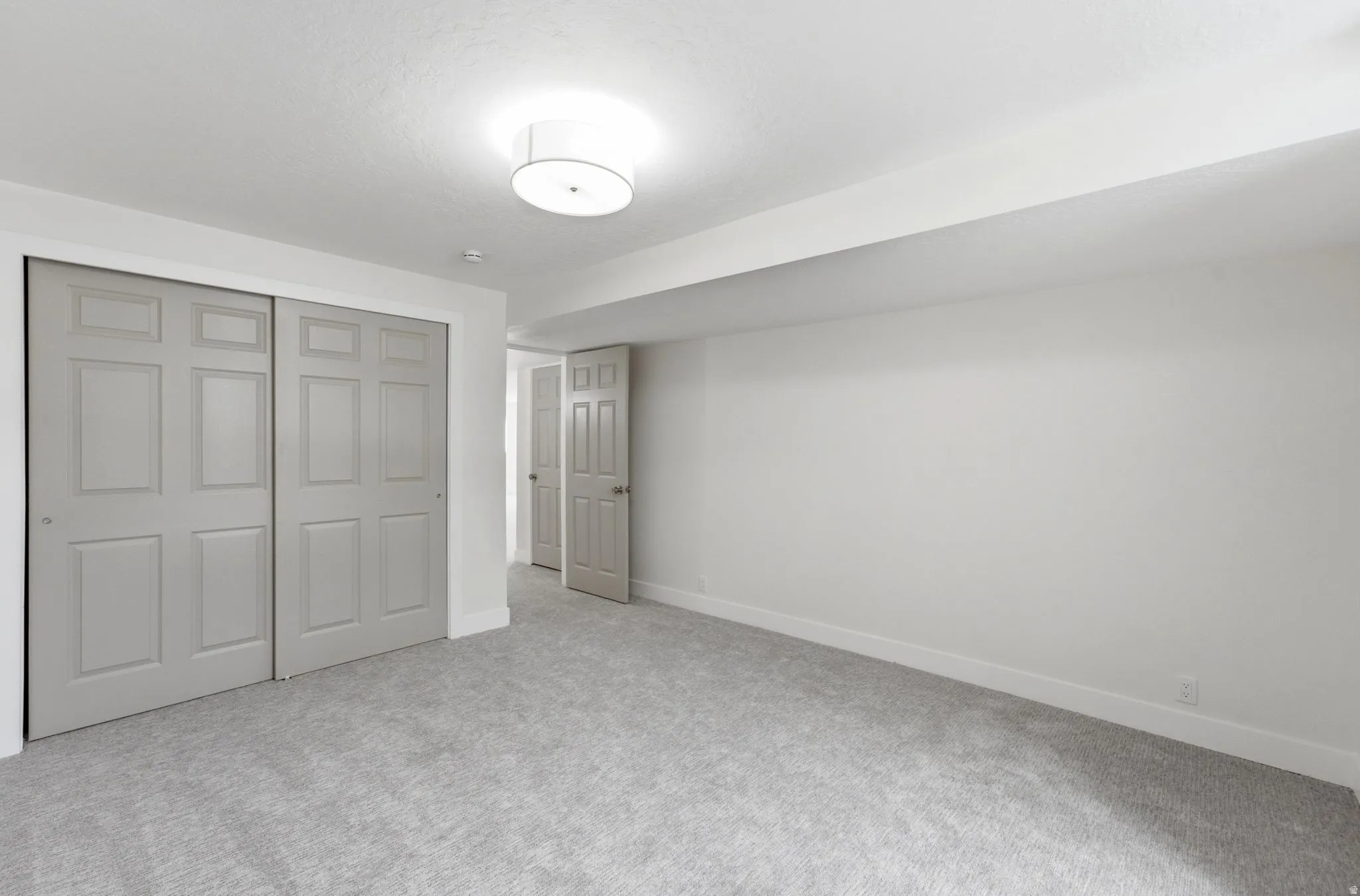 Spacious room with gray carpeting, white walls, and a semi-flush mount ceiling light