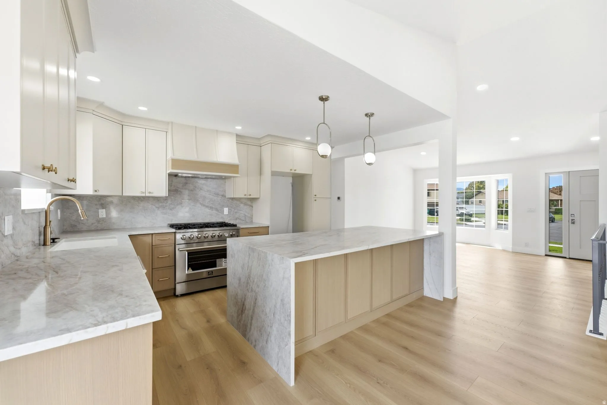 Gourmet kitchen with stainless steel range, marble-finish countertops, wood-finish flooring, and pendant lighting