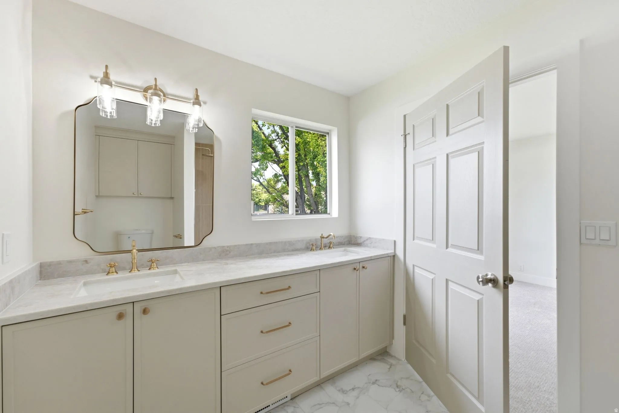 Double vanity with light countertops, dual undermount sinks, and gold-finish fixtures