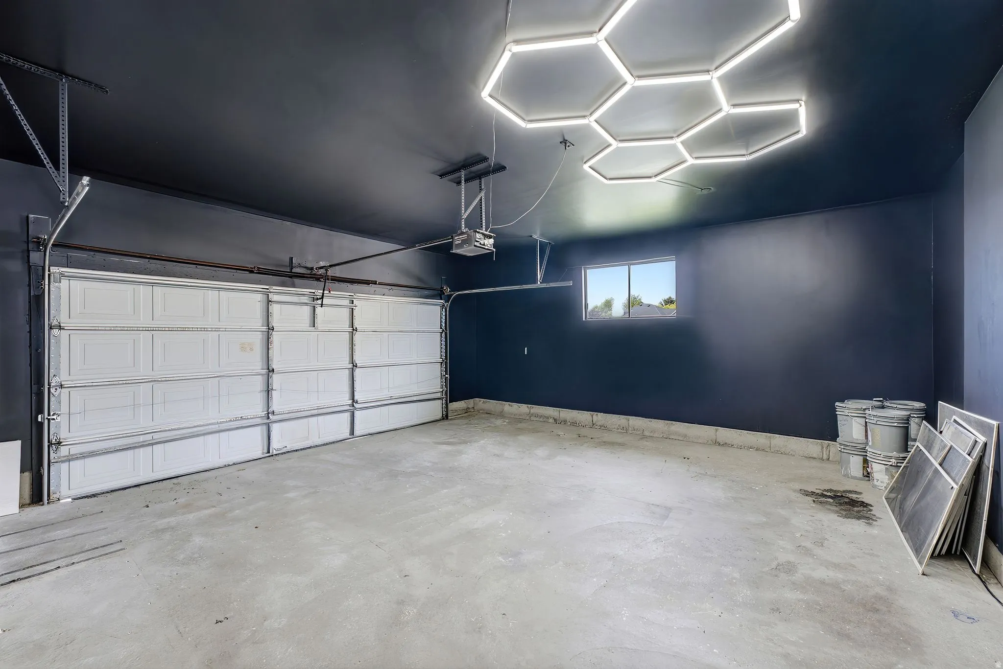 Spacious garage with painted walls, concrete flooring, and a contemporary hexagonal overhead light fixture