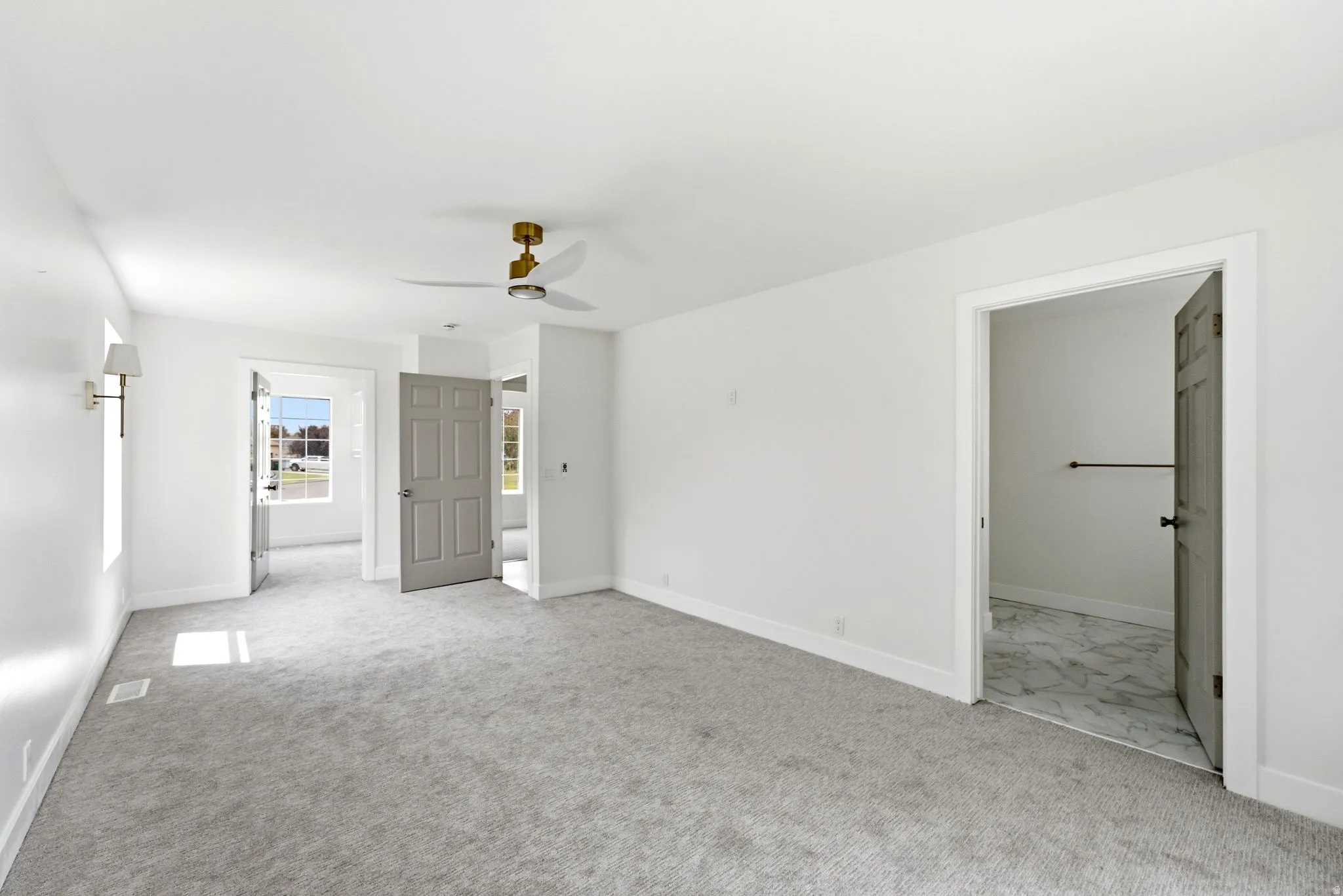 Plush carpet flooring, a ceiling fan with integrated lighting, and a wall sconce