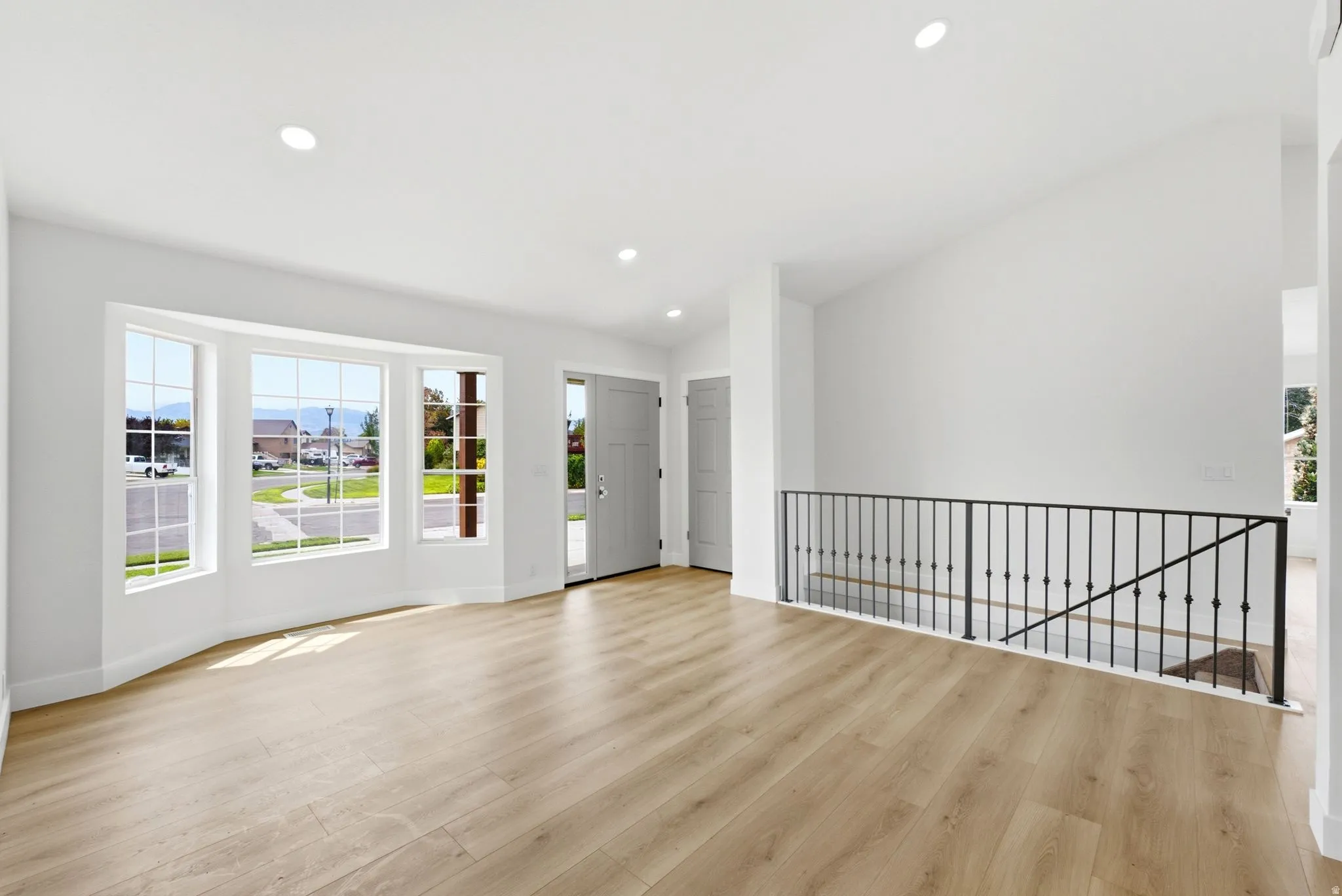 Expansive living area featuring wood-finish flooring, a bay window with multiple panes, and recessed lighting