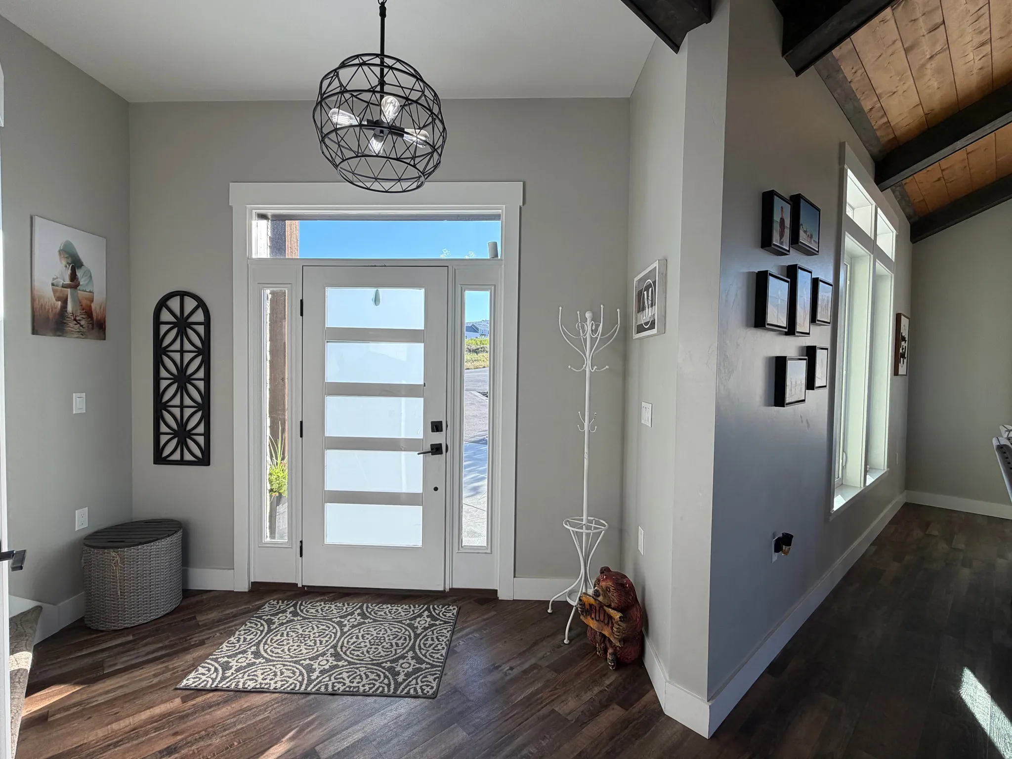 Entry with wood-finish flooring, a contemporary geometric chandelier, and a modern door with opaque glass panels