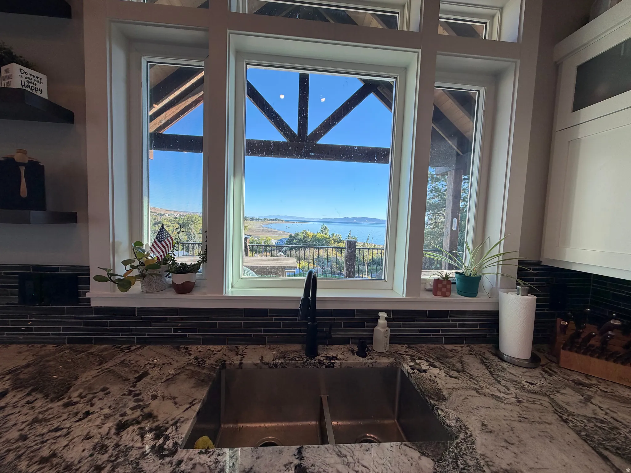 Dual basin stainless steel sink with a matte black faucet, set against a patterned countertop, with a dark tile backsplash