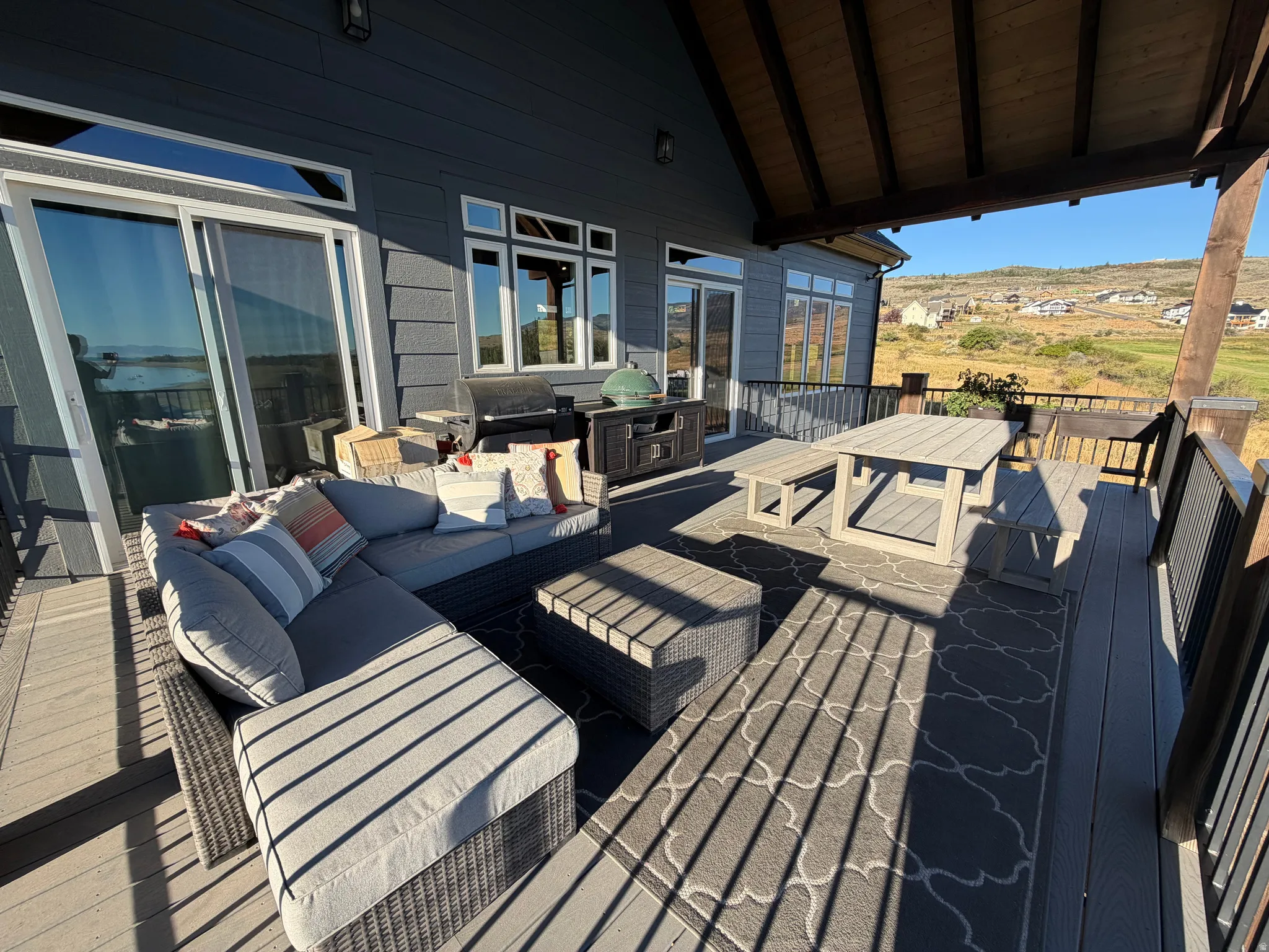 Covered outdoor deck with composite decking, dark wood railing, and a slatted ceiling