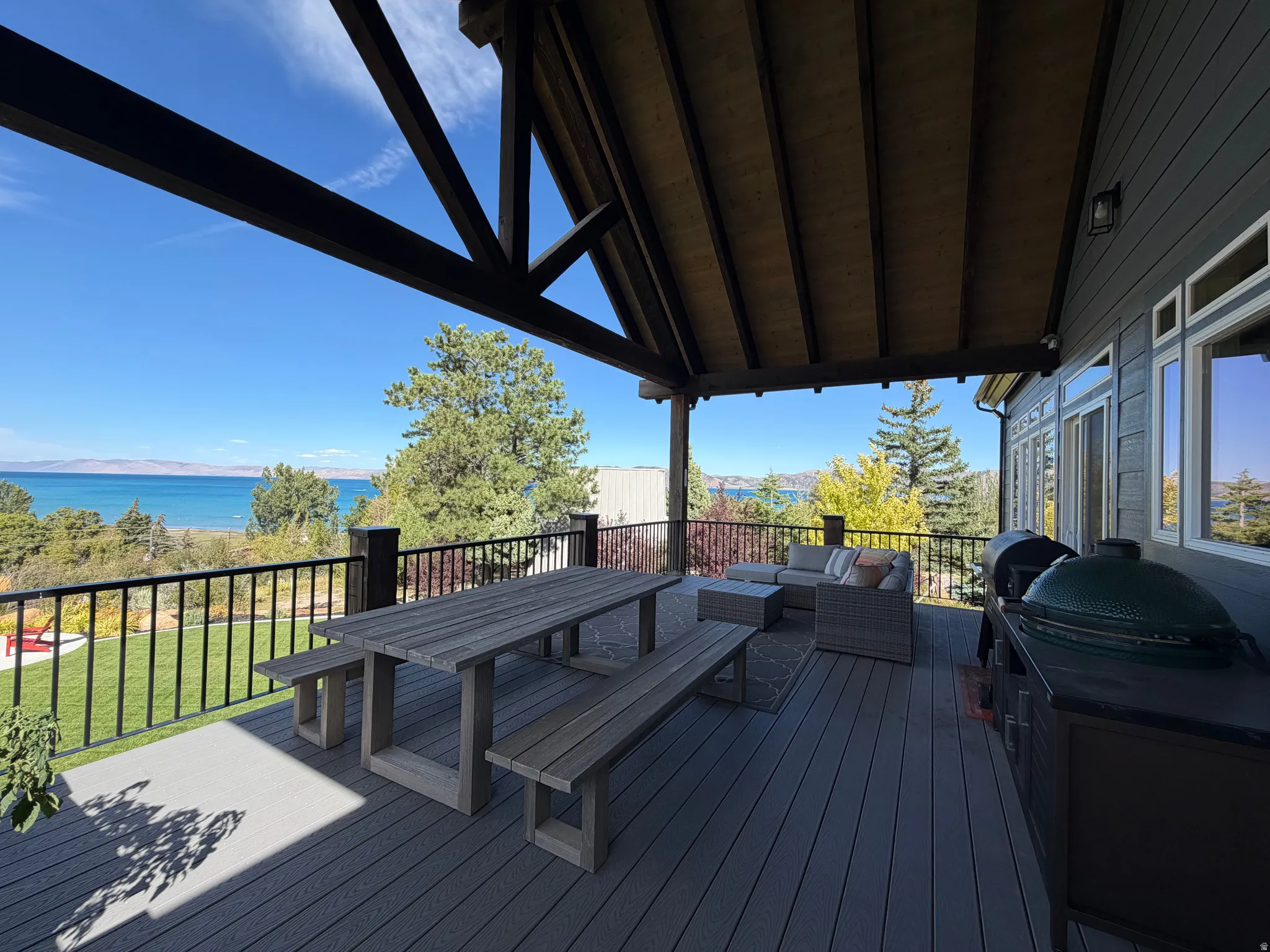 Expansive covered deck featuring a wood-finish ceiling, exposed beams, and a black metal railing