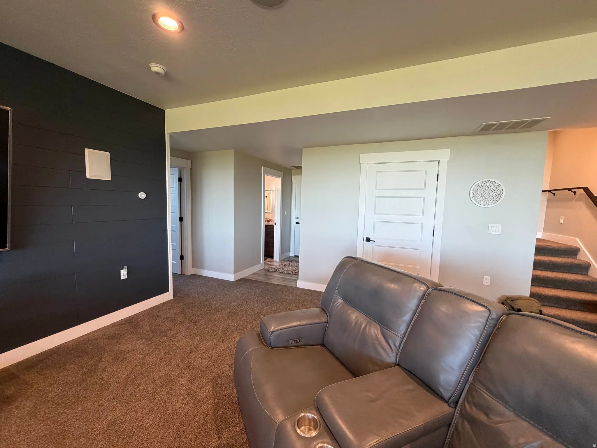 Recessed lighting, wall-mounted speakers, shiplap accent wall, carpeted flooring, and a multi-panel interior door