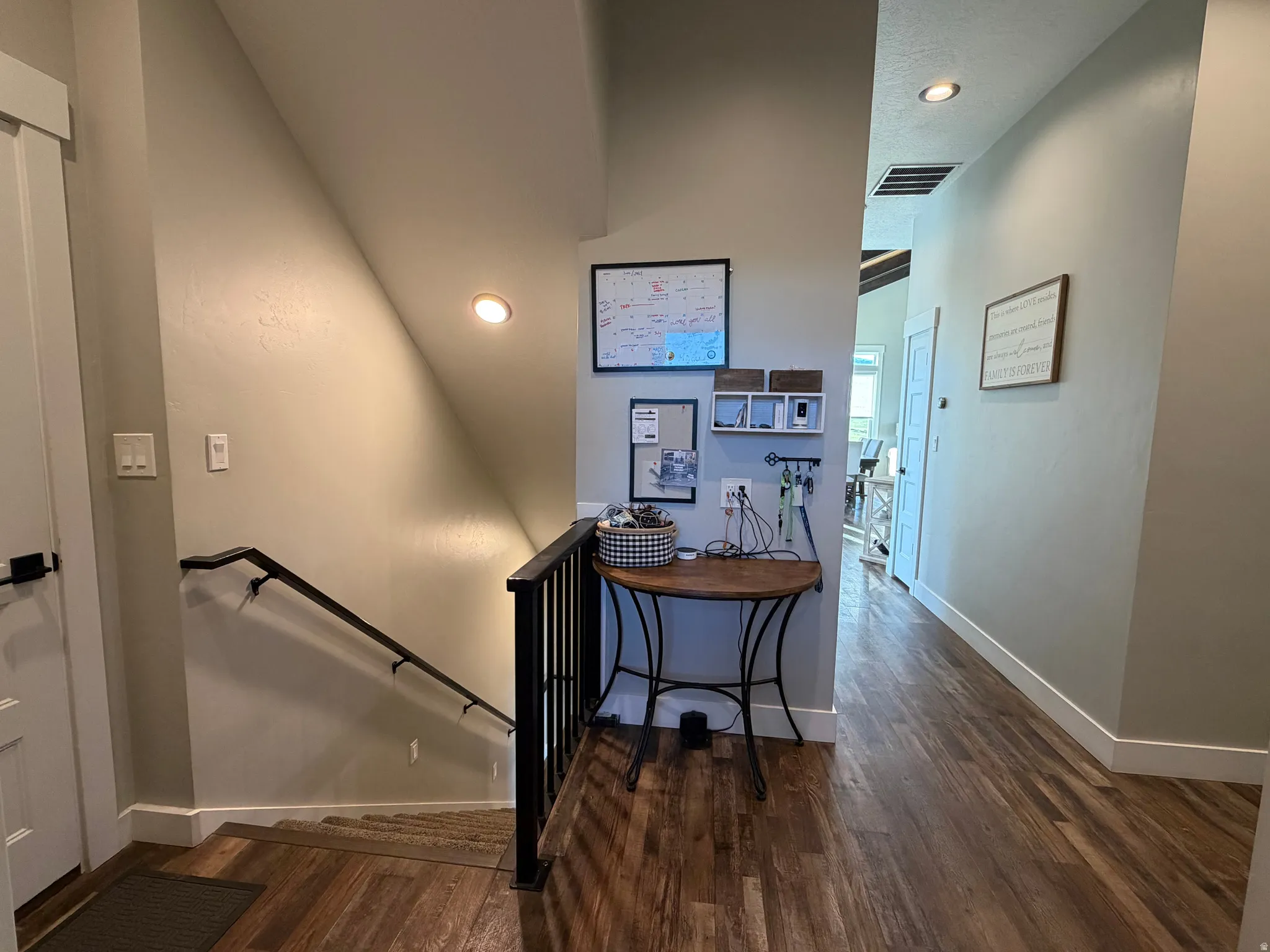 Wood-finish flooring throughout, featuring recessed lighting and a white paneled door