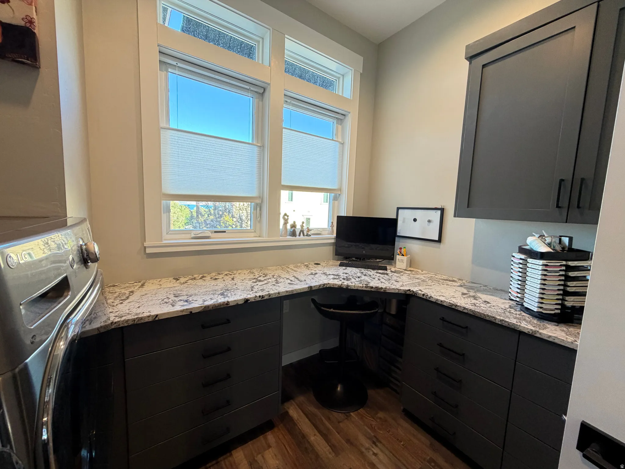 Built-in desk with stone-finish countertop, dark cabinetry, and wood-finish flooring