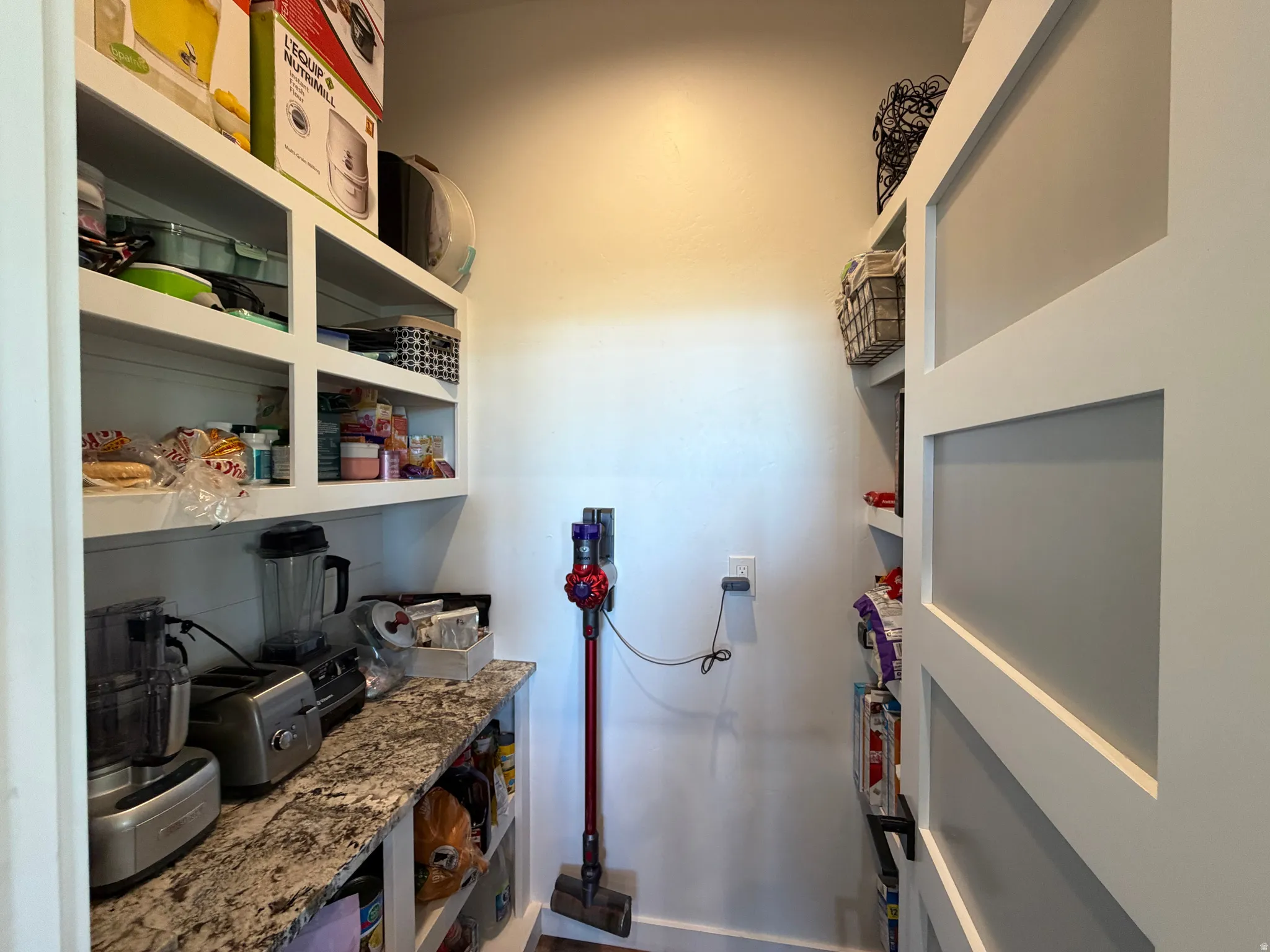 Custom built-in shelving, white cabinetry, solid surface countertop, and sliding paneled doors