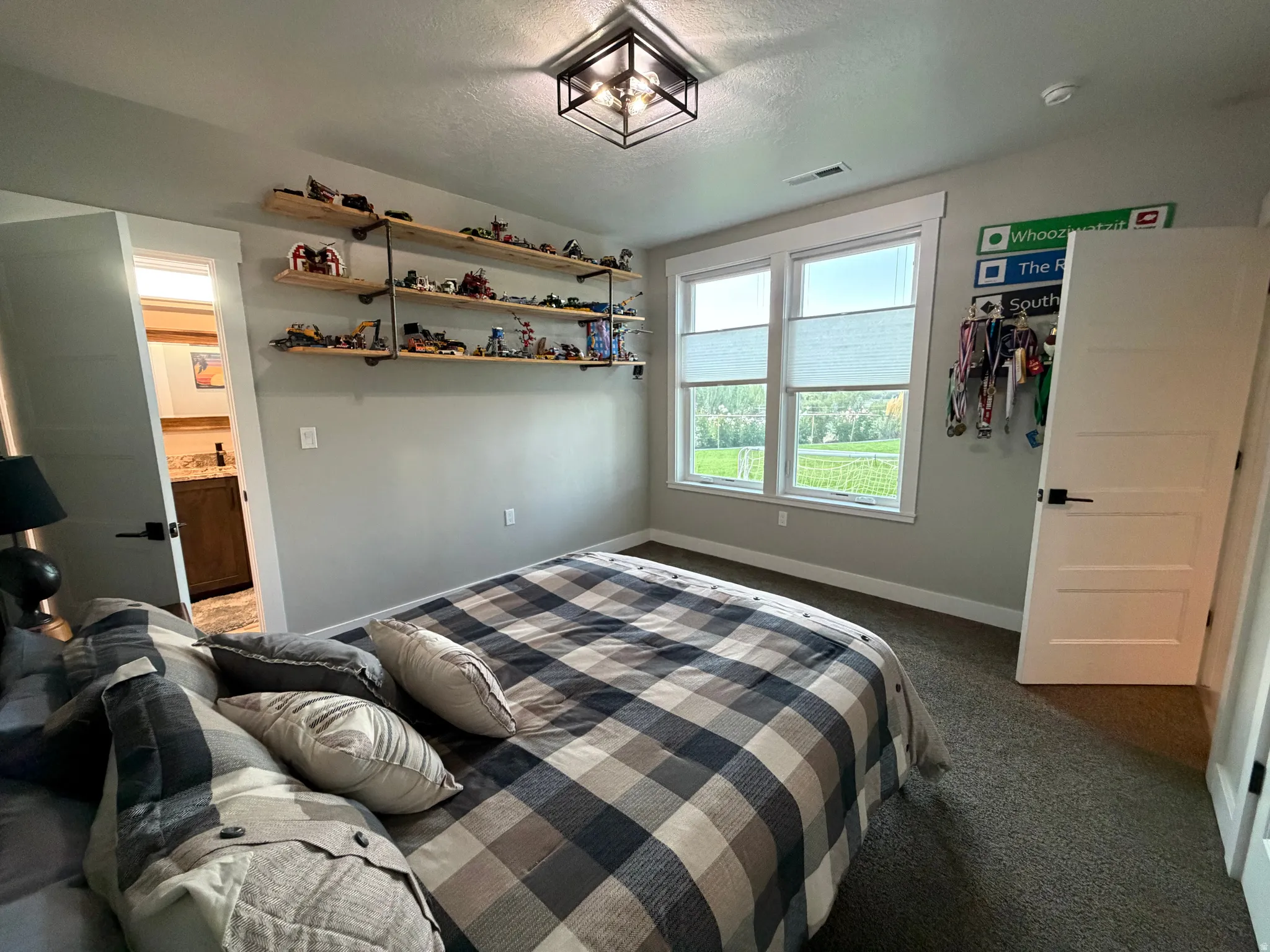 Two-panel window with horizontal blinds, wall-mounted open shelving with metal supports, recessed door, and ceiling-mounted light fixture
