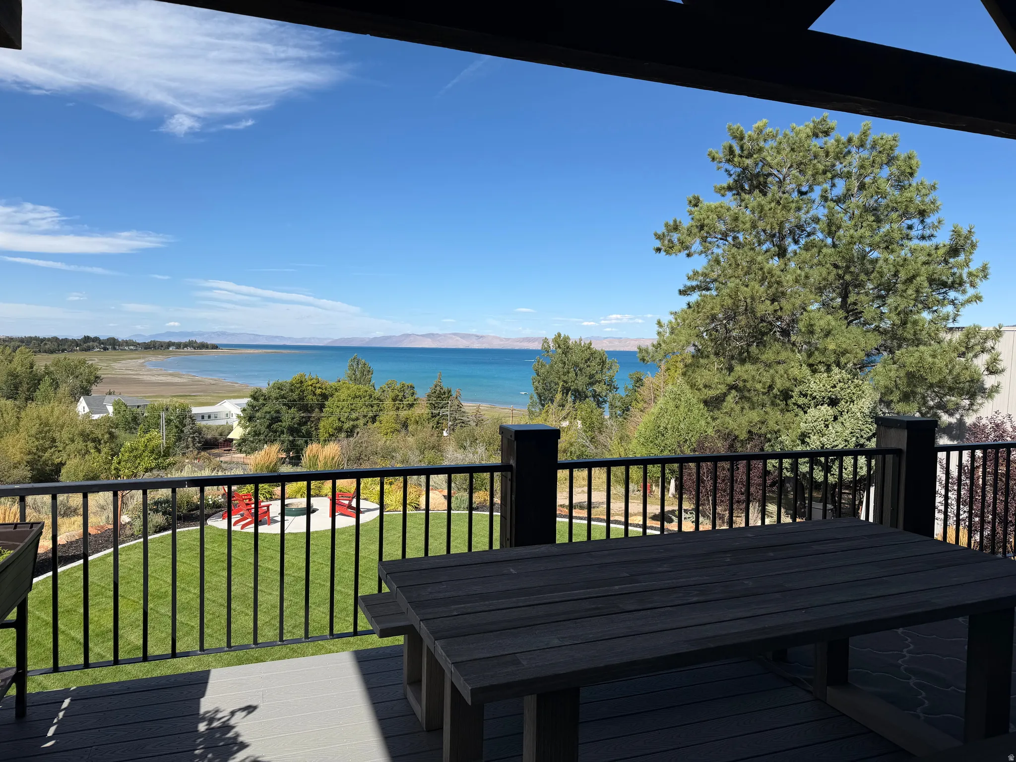 Expansive outdoor deck with black railing and composite decking, offering a broad water expanse and distant mountains