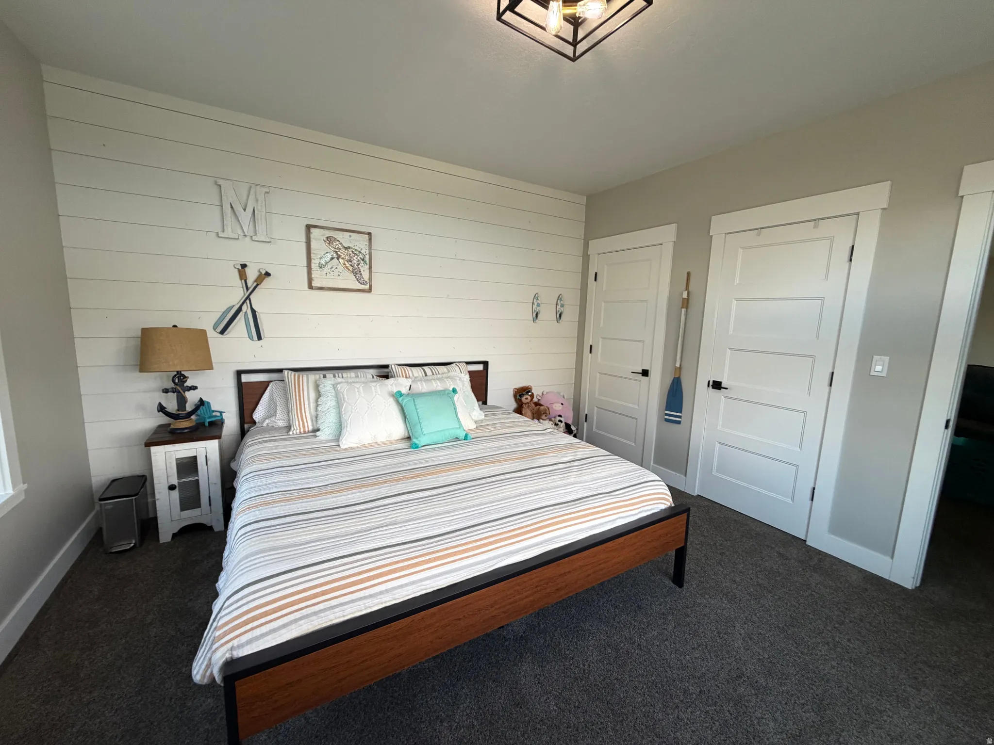 Shiplap accent wall, two paneled doors with black hardware, recessed lighting, and grey carpet