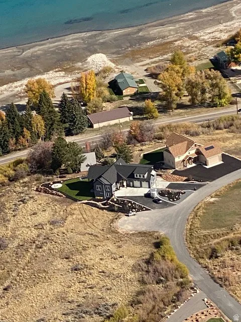 Modern exterior with a dark-pitched roof, attached three-car garage, expansive paved driveway, and tiered landscaping