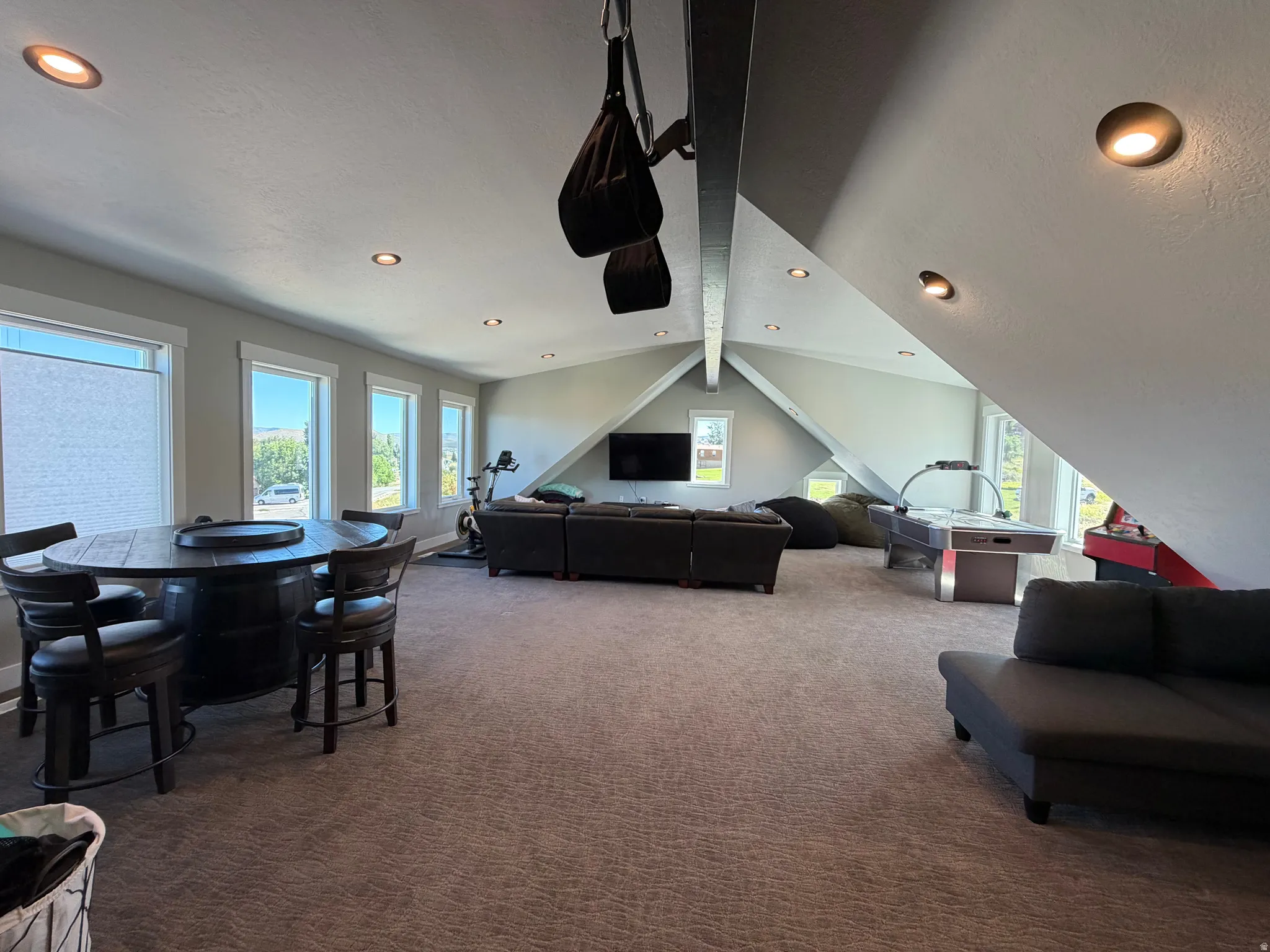 Expansive carpeted room with multiple windows, recessed lighting, and a vaulted ceiling