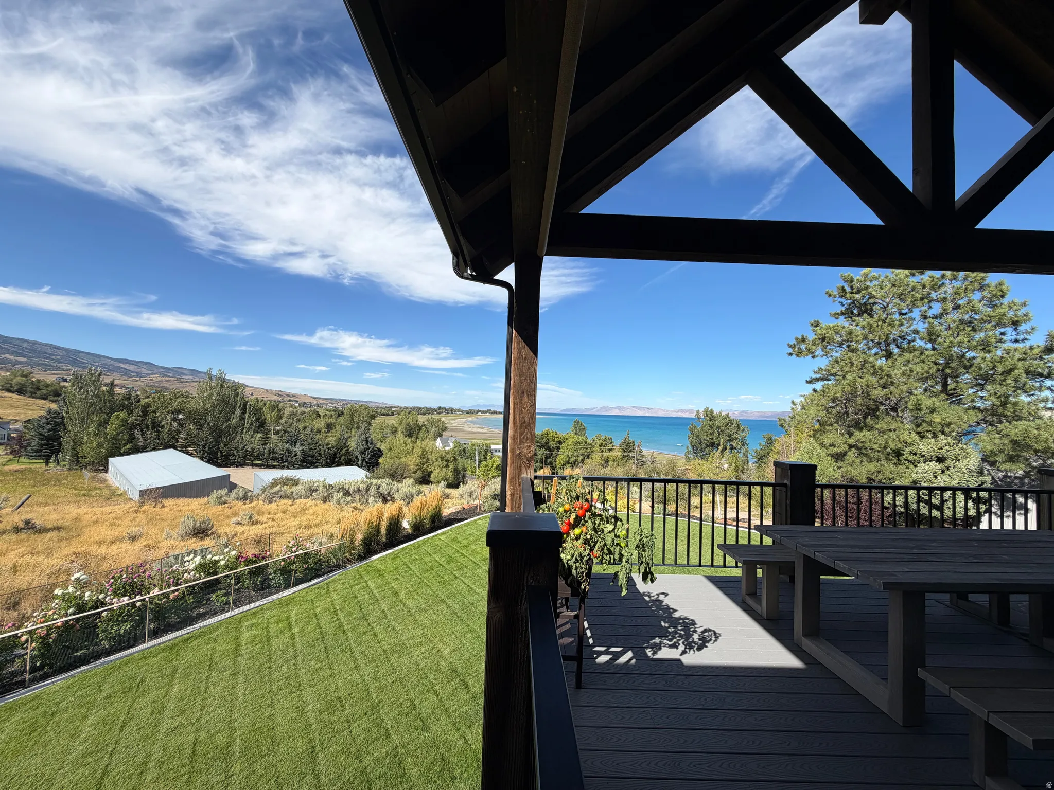 Expansive outdoor deck with composite decking, black metal railing, and a vaulted wood-beam ceiling