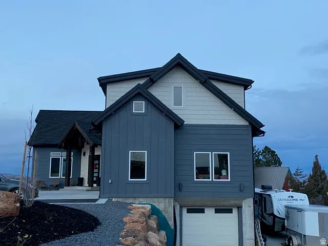 Modern exterior with contrasting board and batten and horizontal siding, dark shingle roof, covered entry, and an integrated garage