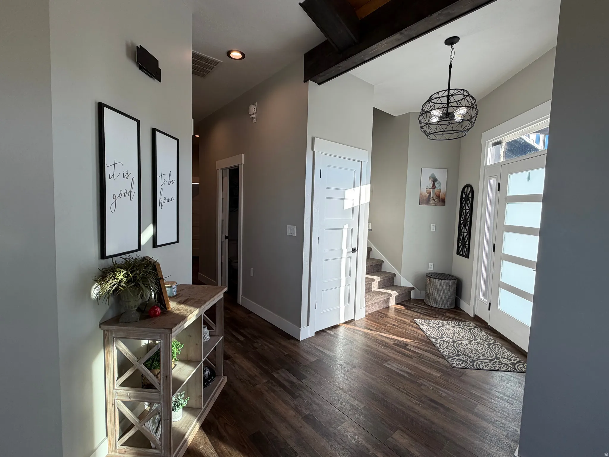 Wood-finish flooring, high ceilings with exposed beams, and a modern spherical chandelier