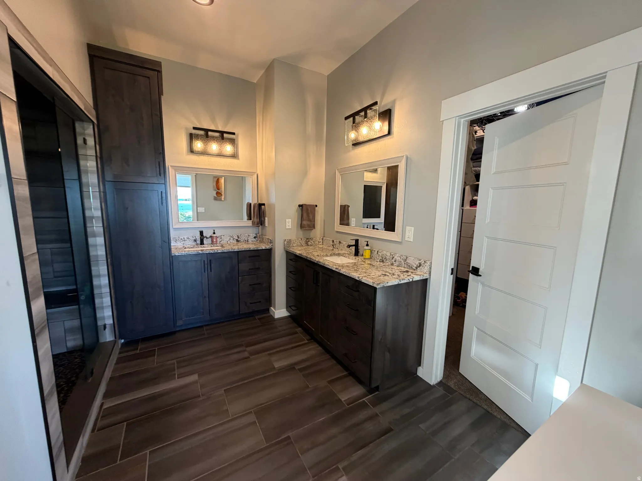 Dual vanities with granite countertops and dark wood cabinetry