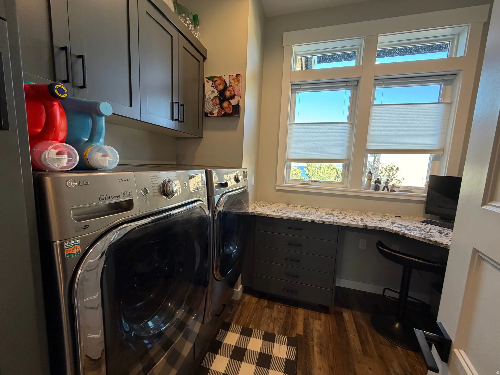 Laundry area with wood-finish flooring and upper cabinetry