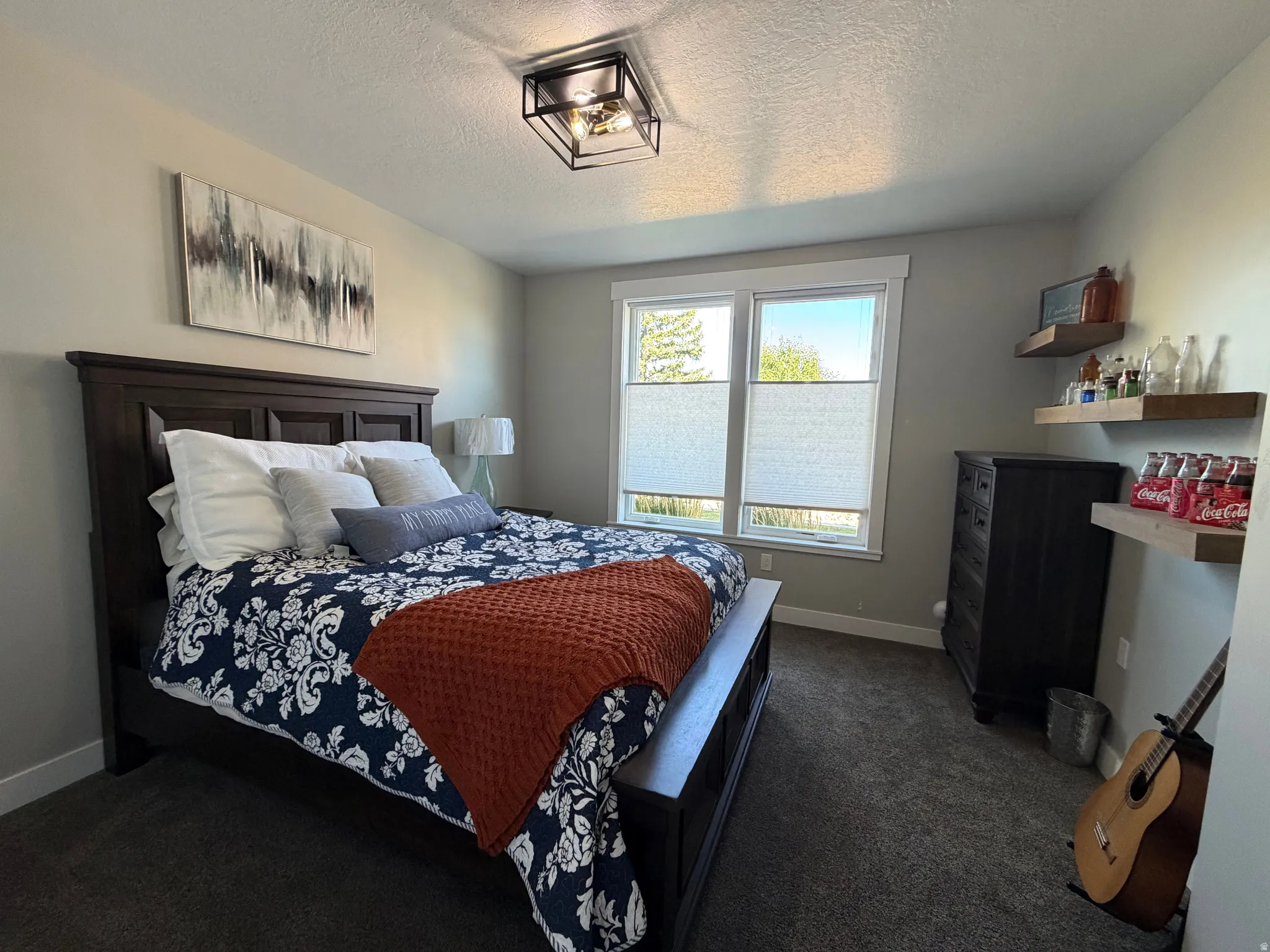 Dark wood bed frame, recessed ceiling light, dual pane windows, and floating wood shelving