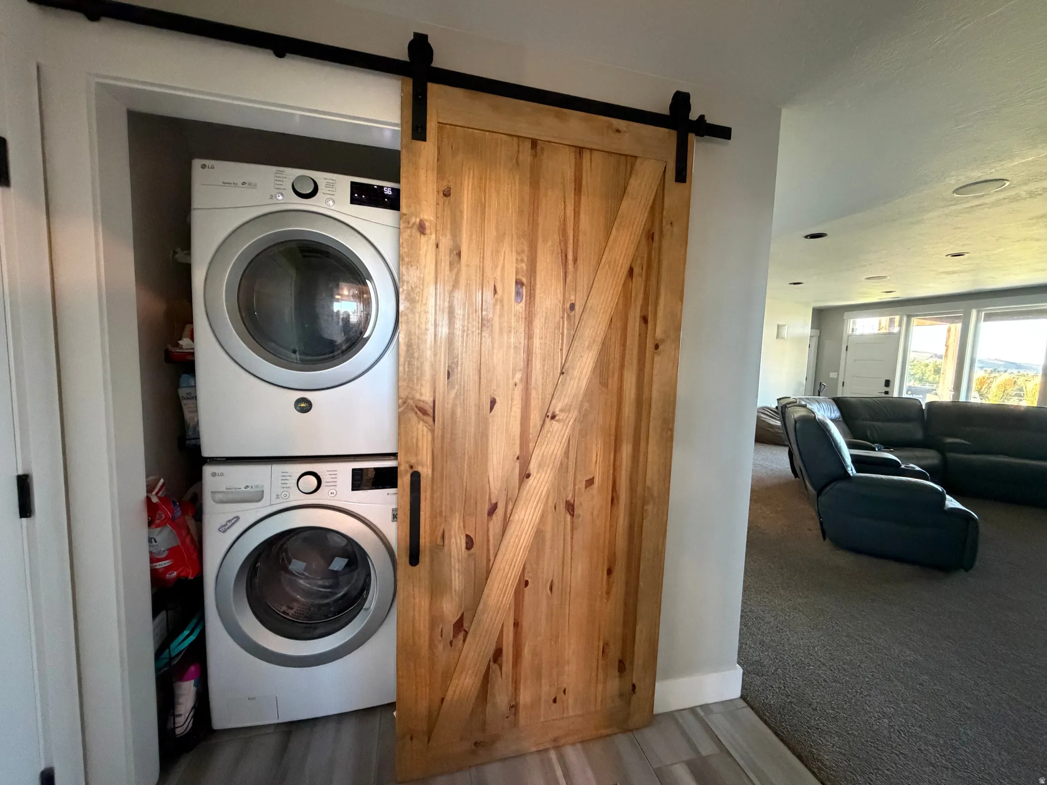 Barn door entry to the laundry area with a stacked washer and dryer