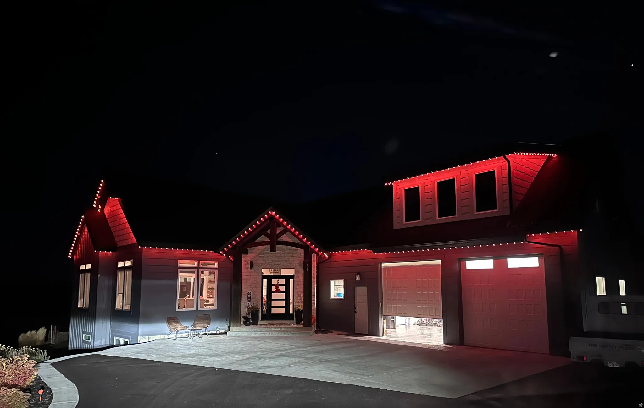 Stone accent entry with wood beam detailing, multi-car garage, and paved driveway