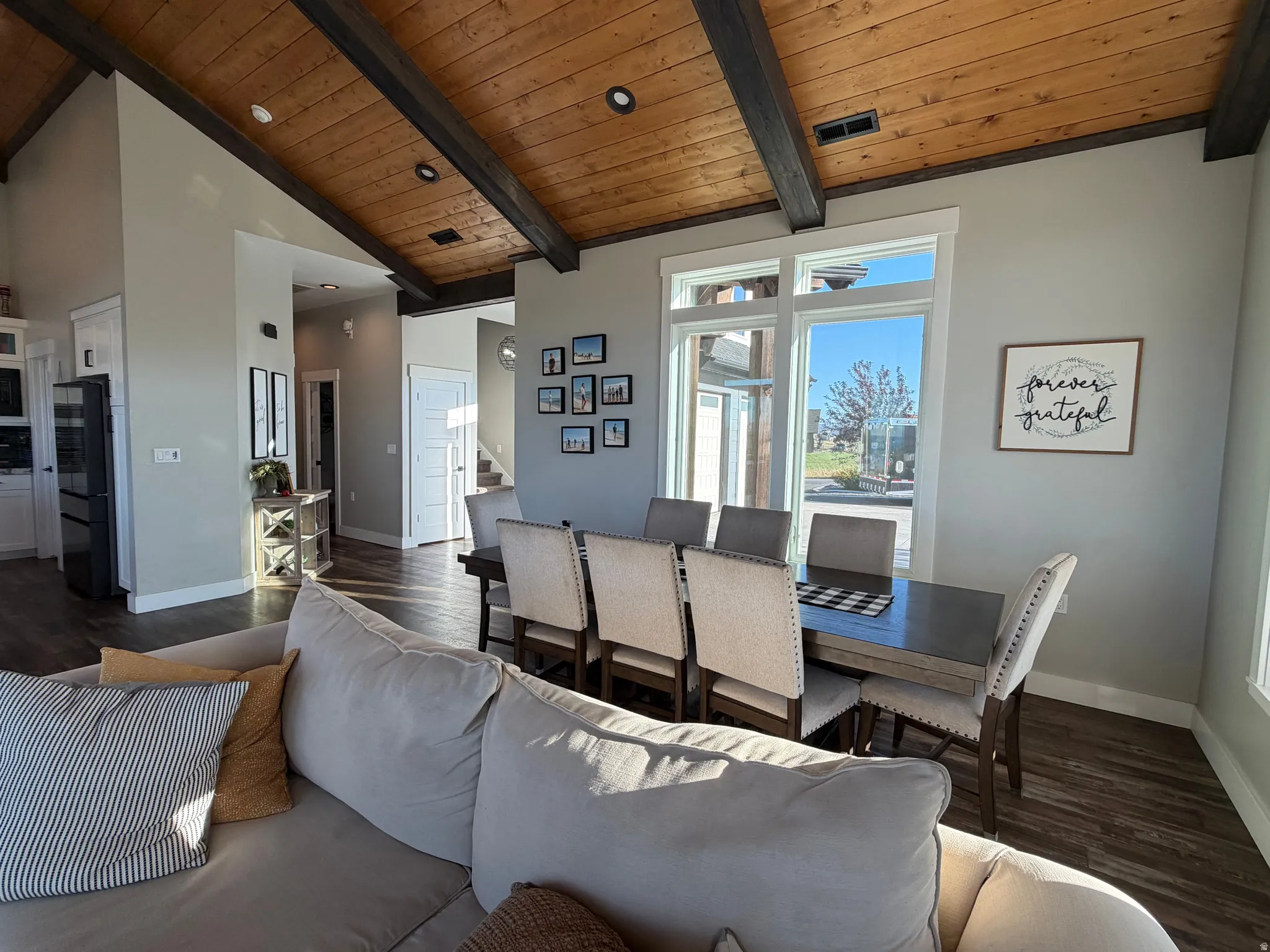 Vaulted wood-finish ceiling with exposed beams, large dining area window, built-in recessed lighting, and wood-finish flooring