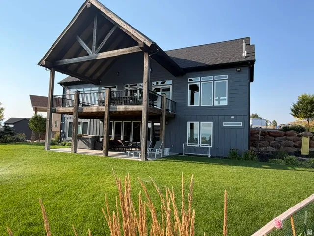 Expansive backyard featuring a lush lawn, a multi-level deck with a covered patio, and a lower-level patio area