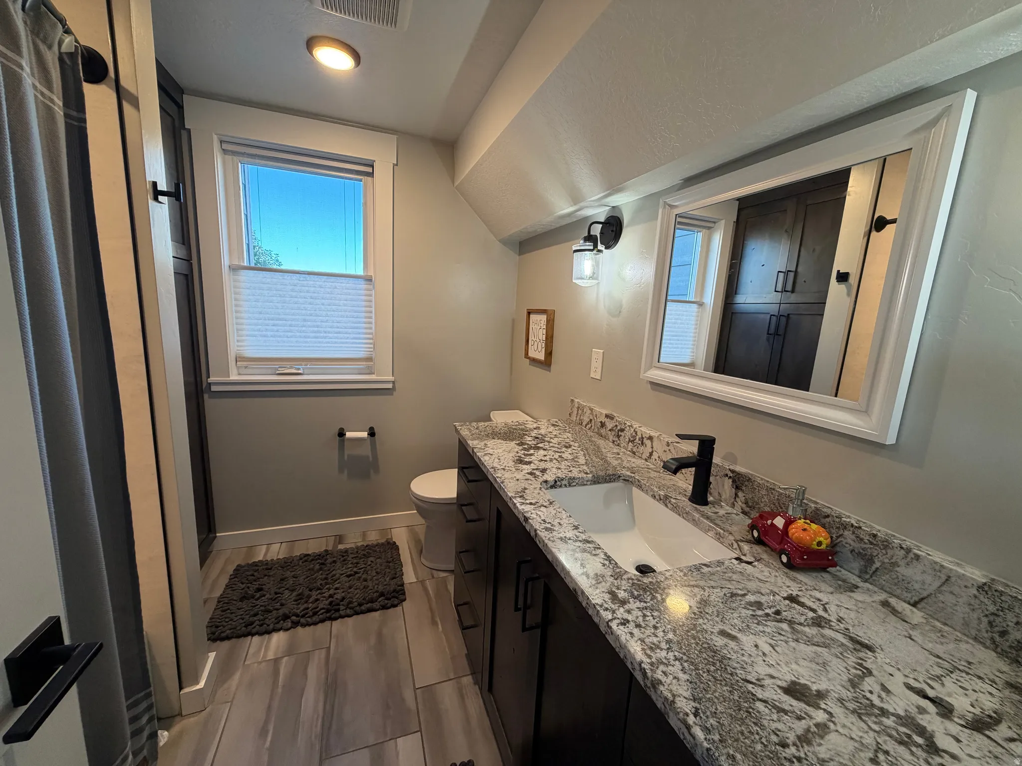 Spacious vanity with a white rectangular undermount sink, granite countertop, and dark wood cabinetry