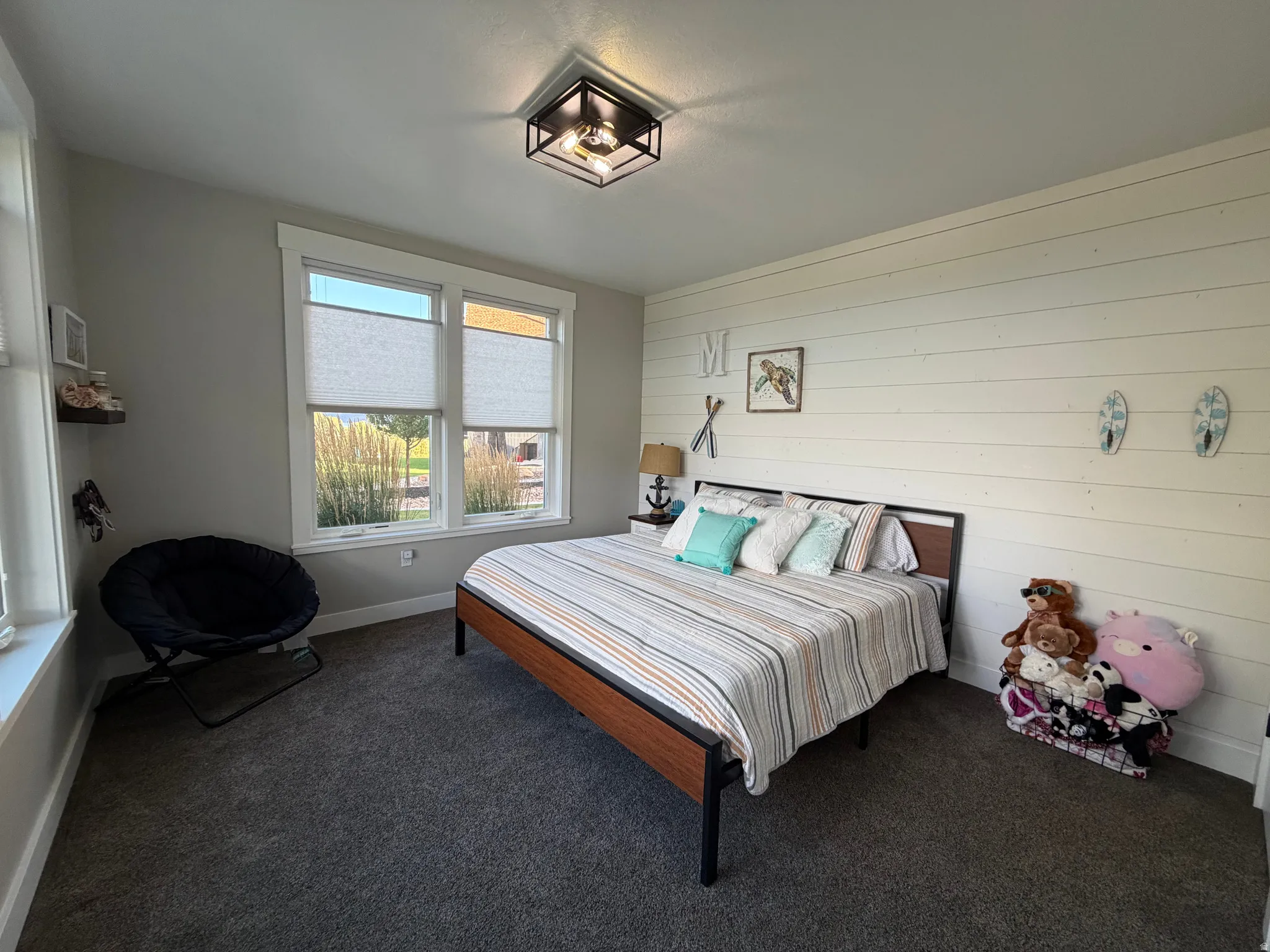 Recessed lighting, broad windows with blinds, gray carpeting, and an accent wall with horizontal paneling