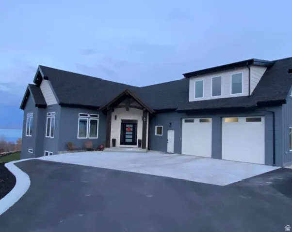 Modern exterior with dark siding, stone accents, a multi-pane front entry door, a two-car garage, and an asphalt driveway