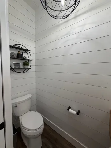 Shiplap wall accents, wood-finish flooring, and a contemporary spherical light fixture