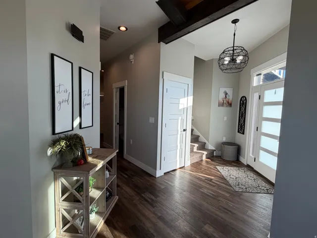 Wood-finish flooring, high ceilings with exposed beams, and a modern spherical chandelier