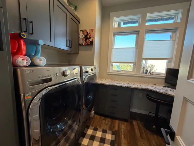 Laundry area with wood-finish flooring and upper cabinetry