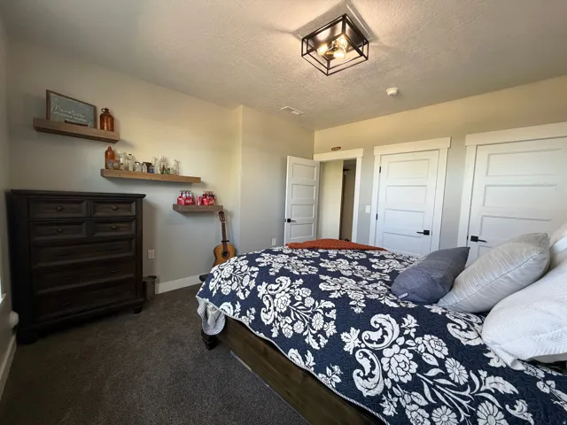 Recessed square ceiling light fixture, wall-mounted floating shelves, white paneled doors with black hardware, and gray carpeting