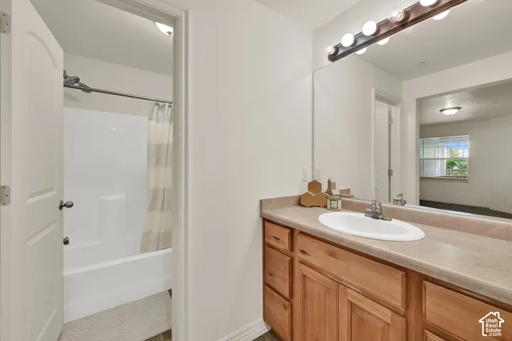 En suite primary bathroom vanity with a single basin sink, wood-finish cabinetry, and a full-width mirror