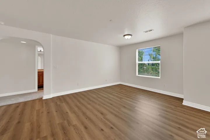 Spacious room featuring laminate wood-like flooring, white walls, and a window with blinds