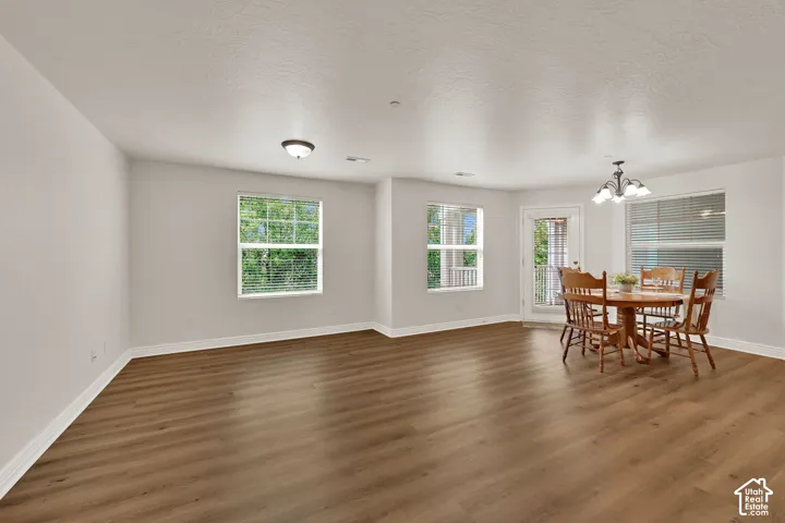 Spacious room featuring laminate flooring, multiple windows with blinds, and a glass-paneled door