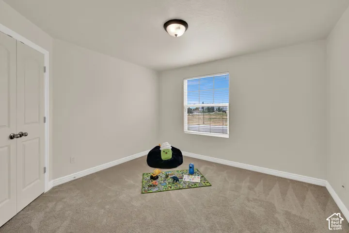 Bedroom 3 with neutral wall color, new carpet, and walk-in closet