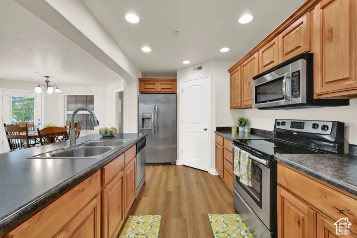 Kitchen featuring wood-finish cabinetry, stainless steel appliances, dark countertops, nice sized pantry, and recessed lighting