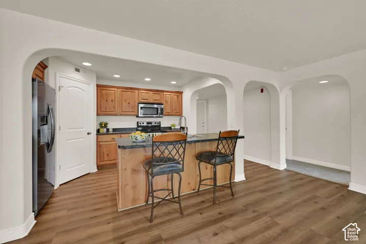 Open-concept kitchen featuring wood cabinetry, stainless steel appliances, and an island